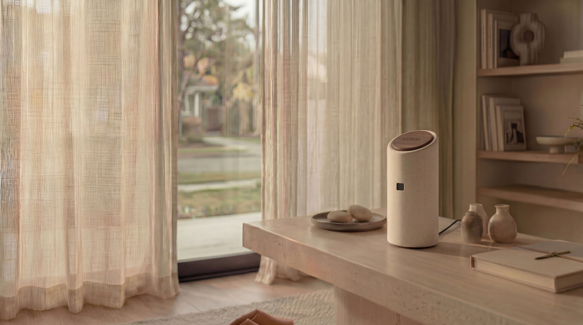 A calm, sunlit living room with sheer linen curtains and the sensea home-care device on a wooden sideboard.