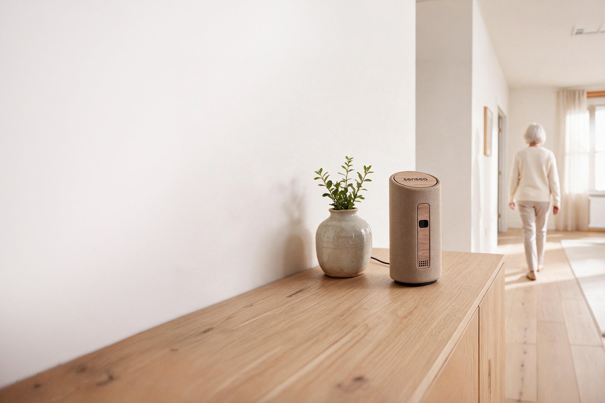 A calm, sunlit living room with the sensea home-care device on a wooden sideboard.